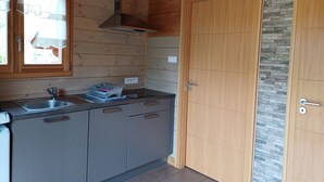 A kitchen with wooden cabinets, a stainless steel sink, and a window with curtains.