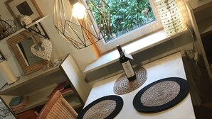 A dining table with two woven placemats, a wine bottle, and a pendant light. - "Idyllic house on the Wadden Sea - peace, nature & adventure for 2- and 4-legged friends" (Jemgum)