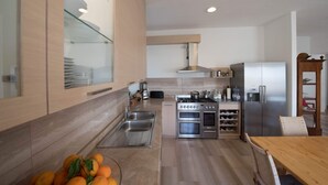 Una cucina moderna con elettrodomestici in acciaio inossidabile, forno integrato e cantinetta per vini.