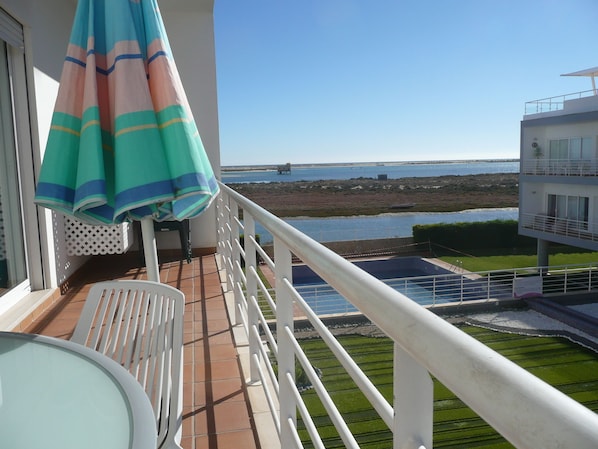Un balcon avec vue sur la mer, une piscine et un immeuble doté d’un balcon.