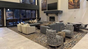 A spacious living area with multiple seating options, a fireplace, and large windows offering views of the outdoors. - The Springs, Extra Large Condo.  Cool winter deals! (Keystone)