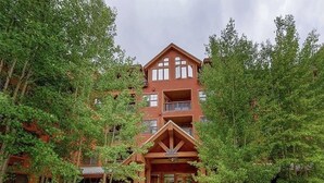 A multi-story building with a central entrance, surrounded by trees. - The Springs, Extra Large Condo.  Cool winter deals! (Keystone)