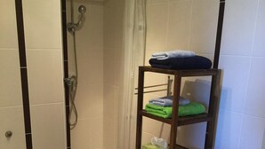A small bathroom with a shower, a toilet, and a shelf with towels and toiletries. - Guest room  for 2 persons in Douarnenez bay  (Plonévez-Porzay)