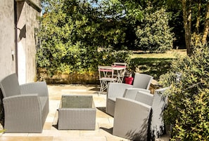 Un patio al aire libre con muebles de mimbre, una mesa plegable y sillas.
