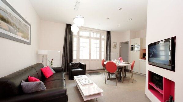 A modern living room with a sofa, dining table, chairs, and a TV.