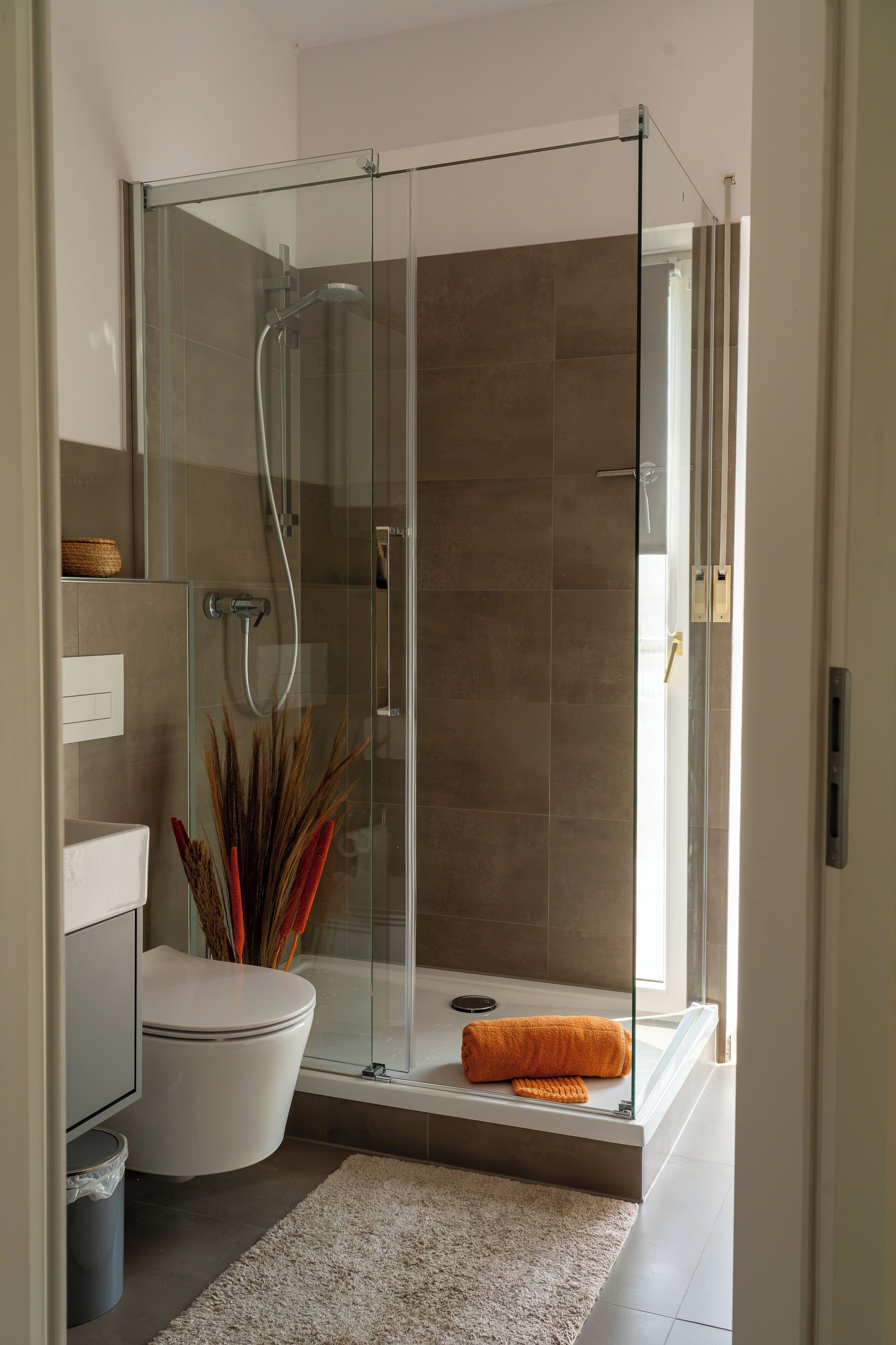 A modern bathroom with a glass-enclosed shower, a toilet, and a bathtub.