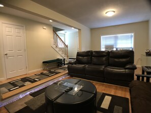 A living room with a leather sofa, a glass coffee table, and a patterned rug.