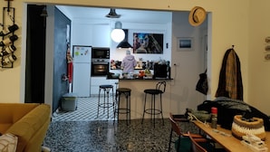 Una cocina moderna con una isla central, un comedor con un taburete de bar y una sala de estar con sofá.