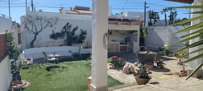 Un patio con césped artificial, una mesa de comedor, sillas y plantas en macetas.