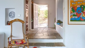 A hallway with a stone floor, a wooden chair, a red cup, and a colorful painting on the wall. - Beatifull seaview / 100m from beach (Amaliapolis)