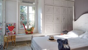 A bedroom with a large bed, a window with a view, a dresser, and a chair. - Beatifull seaview / 100m from beach (Amaliapolis)