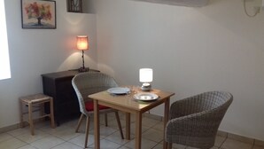 A small dining area with a table, two chairs, a lamp, and a small stool.