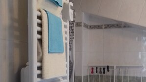 A bathroom with a towel rack, a shower, and tiled walls.