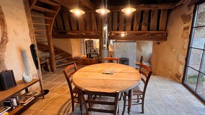 Ein rustikaler Essbereich mit Holztisch und -stühlen, einer Kristallleuchter und einem Steinkamin.