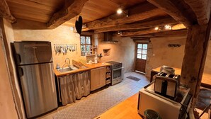 Eine rustikale Küche mit einem Edelstahl-Kühlschrank, Holzarbeitsplatten und einer Steinwand.