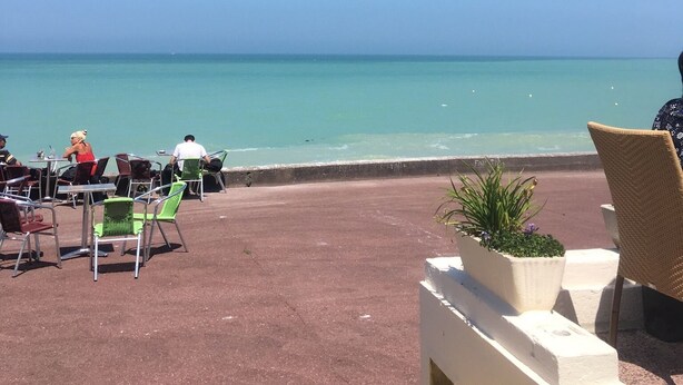 Un espace extérieur aménagé avec des tables et des chaises, donnant sur une plage.