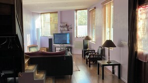 Un salon moderne avec un téléviseur à écran plat, un canapé, une table basse et un escalier.