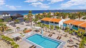 A resort with a swimming pool, palm trees, and a view of the ocean. - Your Place In Paradise! Just steps to private dive beach and resort pool (Kralendijk)