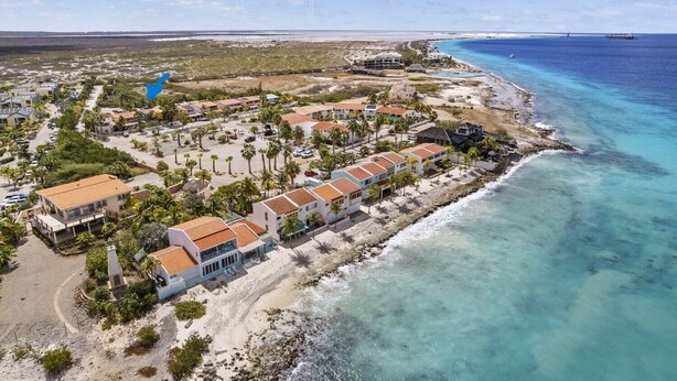 An aerial view of a coastal resort with beachfront villas, palm trees, and a clear blue ocean. - Your Place In Paradise! Just steps to private dive beach and resort pool (Kralendijk)