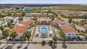 A resort with multiple buildings, a central pool, and palm trees. - Your Place In Paradise! Just steps to private dive beach and resort pool (Kralendijk)