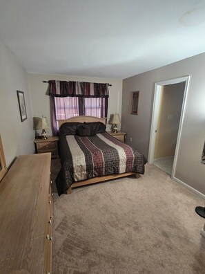 A bedroom with a bed, two bedside tables, a dresser, a window with curtains, and a door. - Blue Ridge Beauty Home Dog Friendly, Walk to Rivers, A.T. Trail, & HF. NEW LVP (Bolivar)