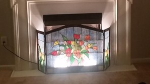 A fireplace with a stained glass design, a mantel with a bull's head decoration, and a wall-mounted painting above. - Blue Ridge Beauty Home Dog Friendly, Walk to Rivers, A.T. Trail, & HF. NEW LVP (Bolivar)