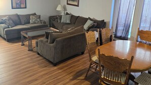 A living room with a sofa, a coffee table, and a dining table with chairs. - Blue Ridge Beauty Home Dog Friendly, Walk to Rivers, A.T. Trail, & HF. NEW LVP (Bolivar)