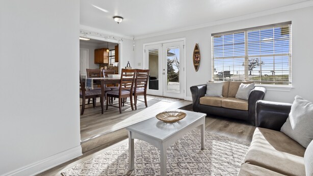 A spacious living room with a sofa, a coffee table, and a dining area with chairs and a table. - Finley House with Beautiful Gulf View (Gulfport)