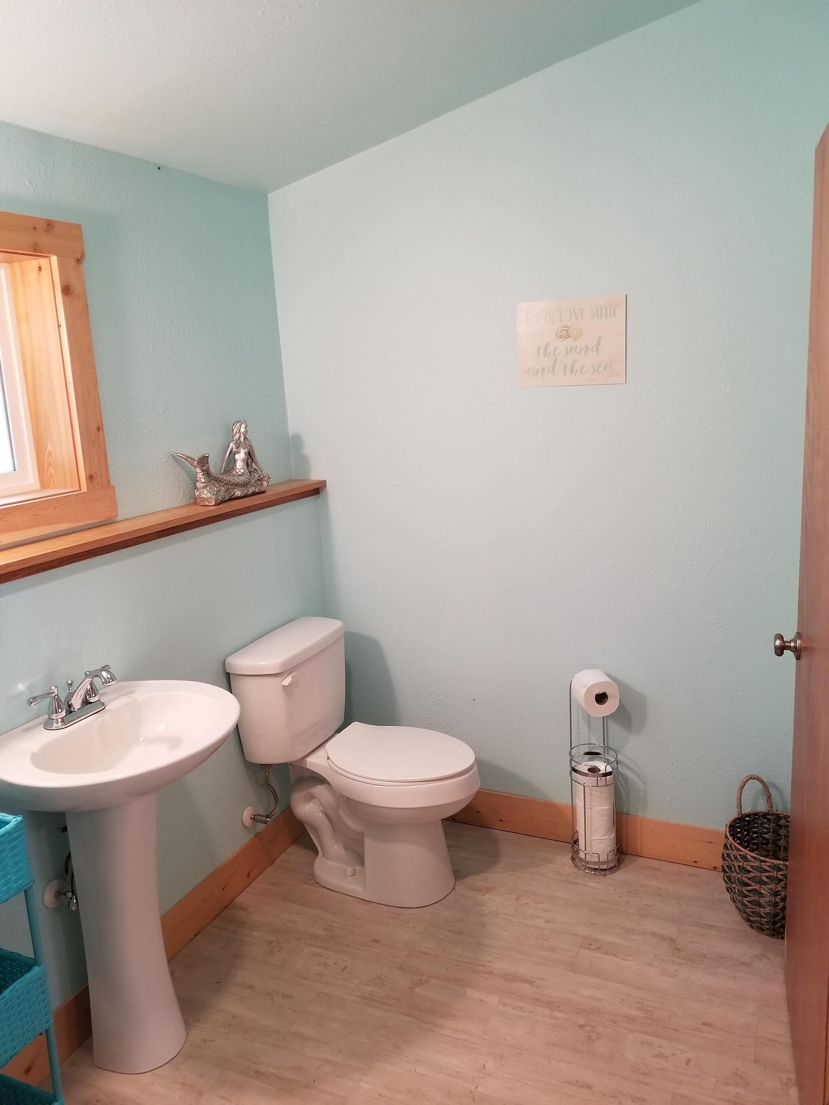 Un baño con lavamanos, inodoro y un estante con objetos decorativos.