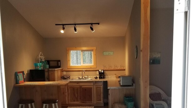 Una cocina acogedora con armarios de madera, un ventanal y una zona de comedor con taburetes.
