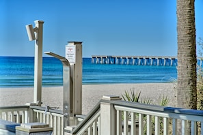 A beach view with a pier in the background and a sign that reads "Calypso Help Pres Beach."