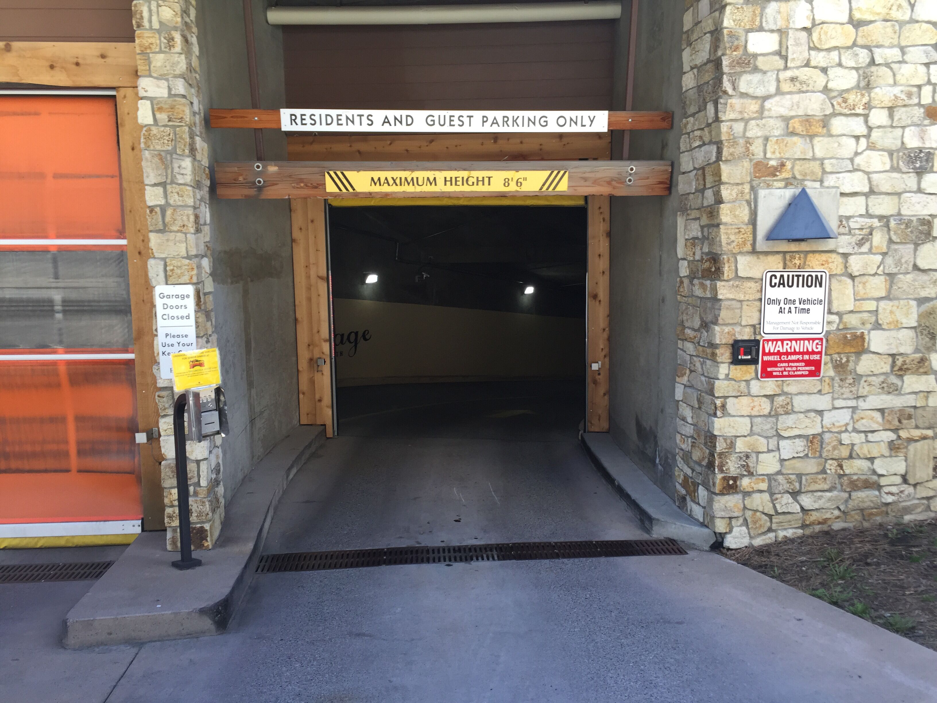 Eine Garageneinfahrt mit einem Schild, auf dem 'RESIDENTS AND GUEST PARKING ONLY' und ein Schild mit der Aufschrift 'CAUTION Only One Vehicle At A Time' stehen.