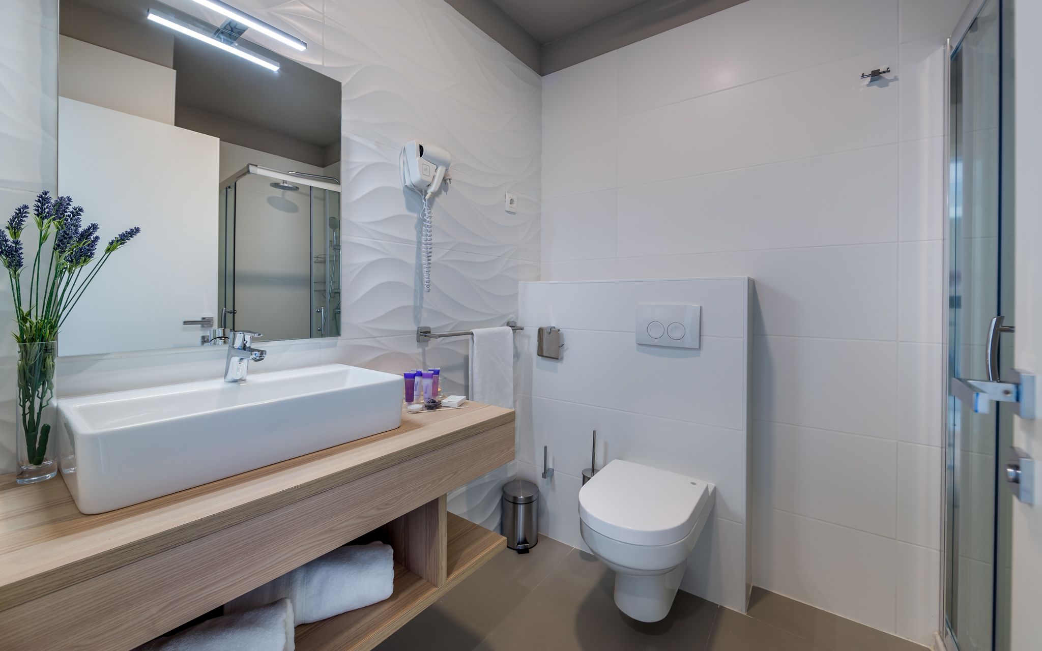 A modern bathroom with a large sink, mirror, and shower.