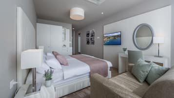 A modern bedroom with a bed, bedside tables, a TV, a mirror, and a sofa.
