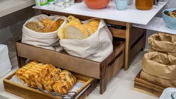 A breakfast buffet with bread, pastries, and dairy products.