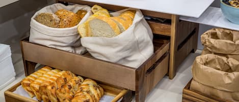 A breakfast buffet with bread, pastries, and dairy products.