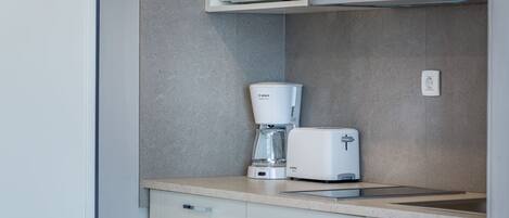 Une cuisine équipée d’un four à micro-ondes, d’une machine à café et d’un grille-pain, le tout posé sur le plan de travail.