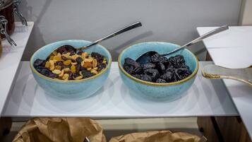Two bowls of dried fruits on a white countertop.
