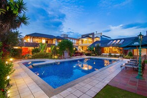 Una piscina rodeada por un jardín cuidado y un edificio con varios balcones.