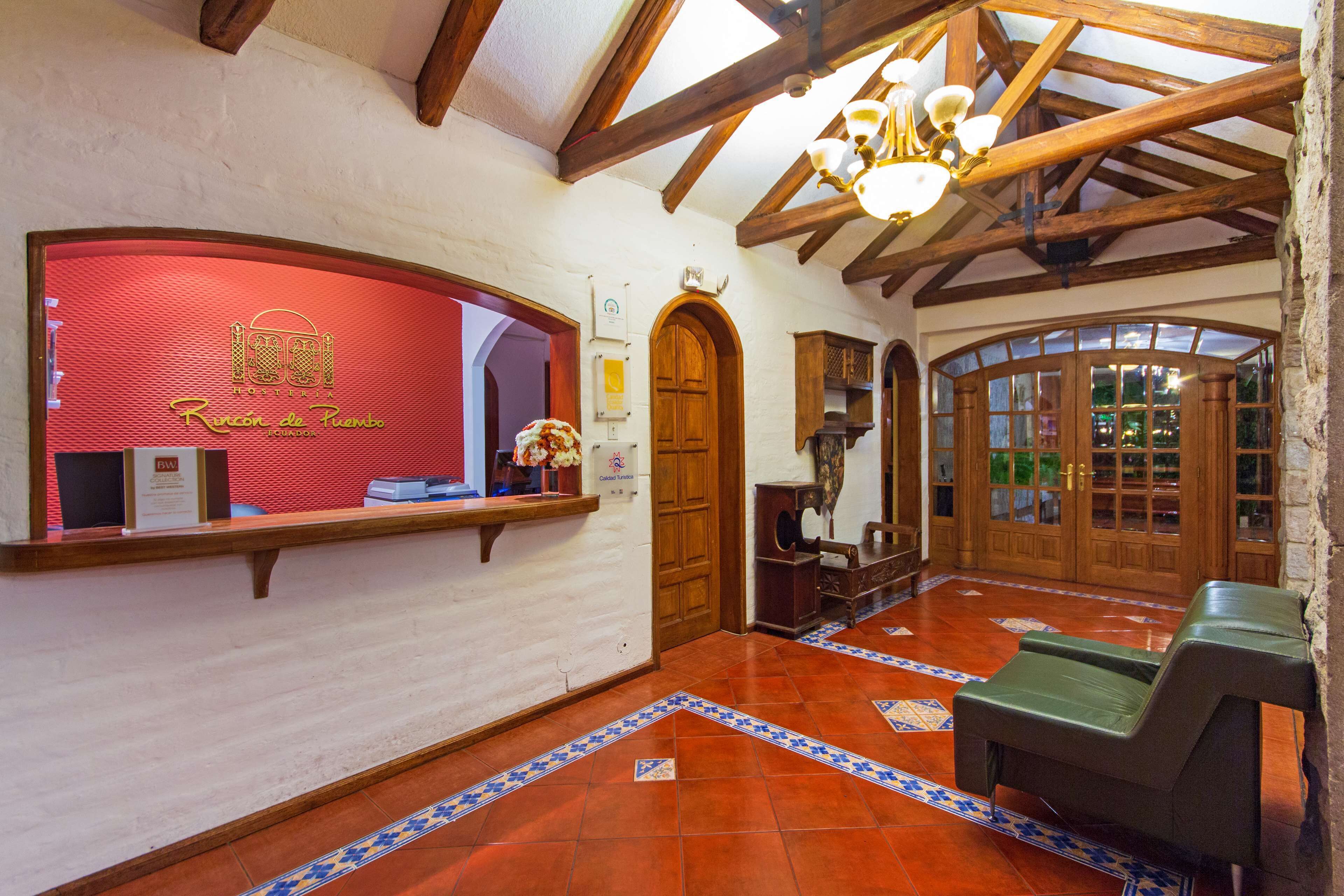 A reception area with a red counter, wooden beams, and a chandelier.