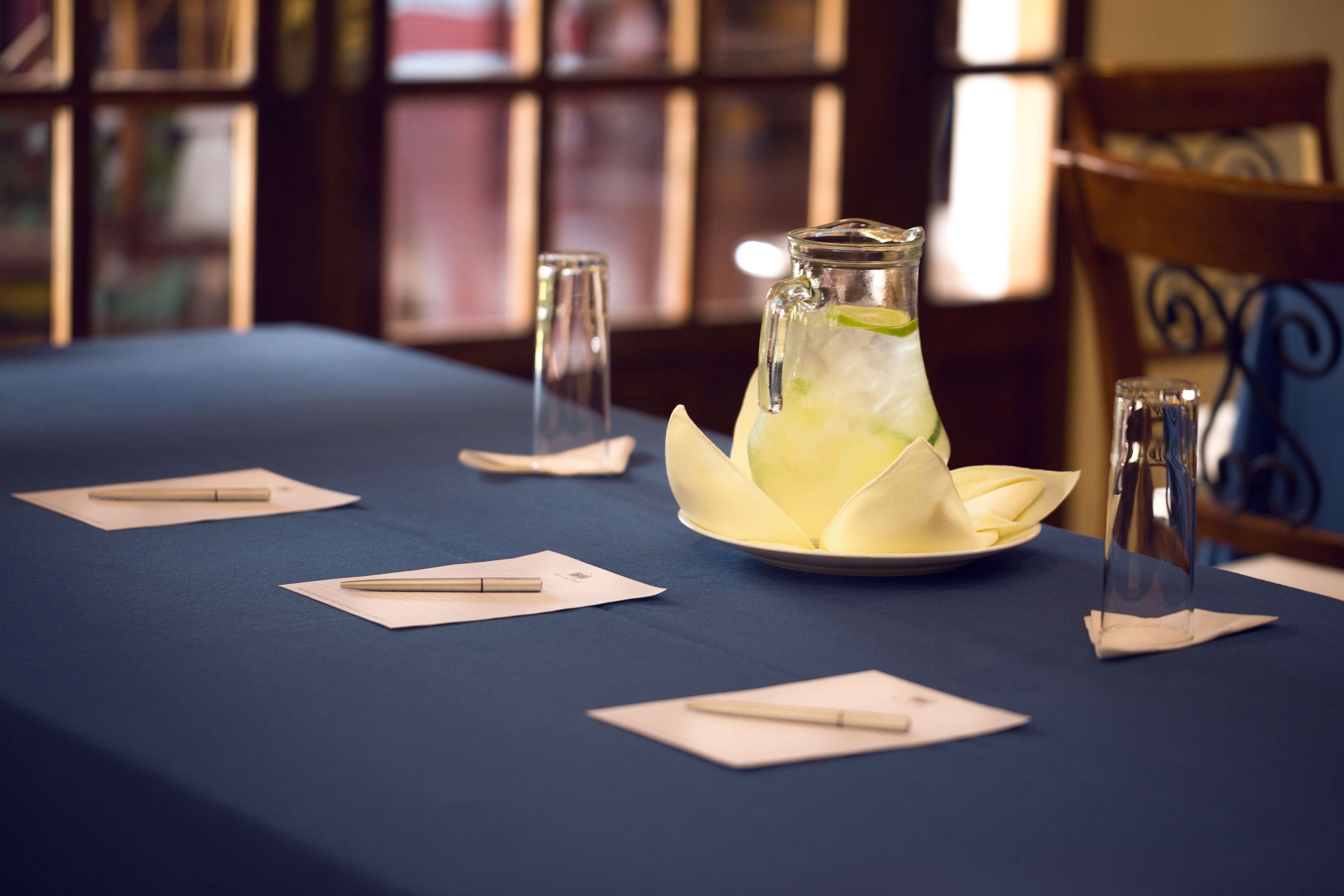 A table set with a pitcher of water, glasses, and napkins.