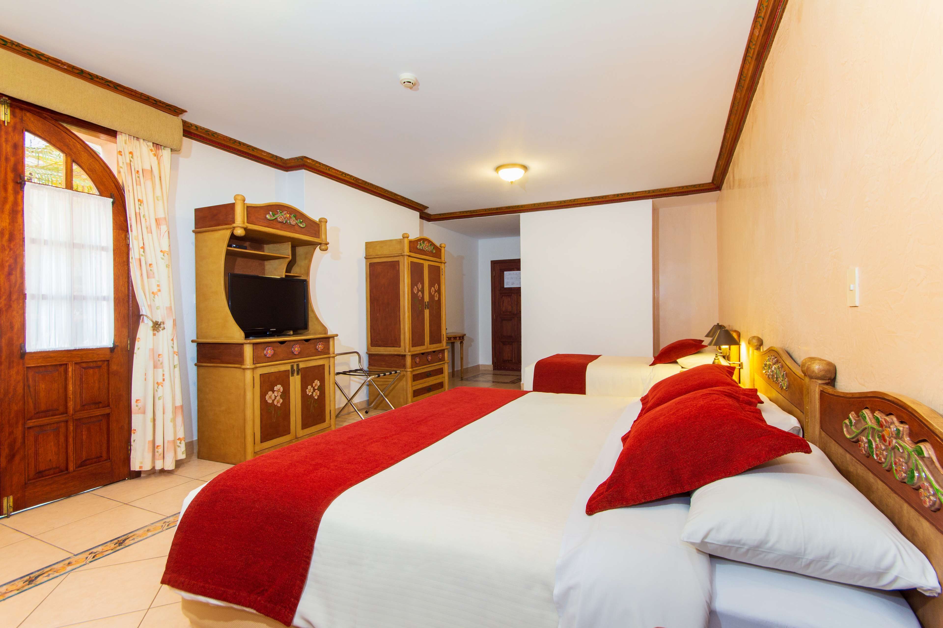 A hotel room with a large bed, wooden wardrobe, and a television.