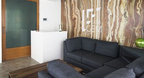 A modern living room with a sectional sofa, a white console table, and a marble-patterned wall.