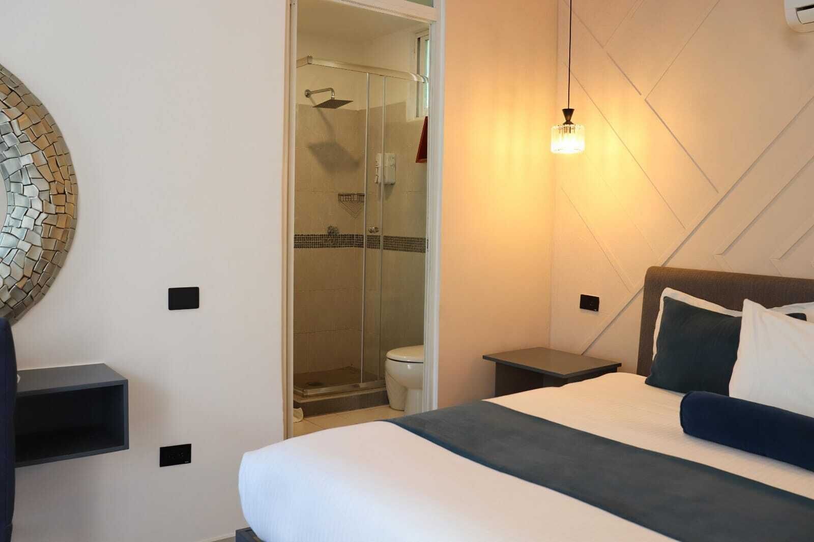 Ein Hotelzimmer mit Bett, Nachttischen, einer Dusche und einer Wandleuchte.