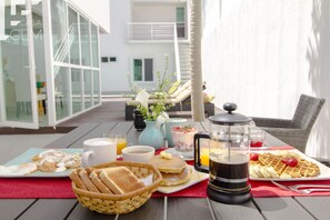 Una mesa de desayuno con tortitas, gofres, tostadas, café y jugo.