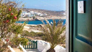 A coastal view with white buildings, a clear blue sea, and a green door. - Pahivouni Studios & Suites (Naxos)