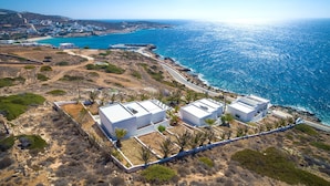 A coastal property with white buildings, a clear view of the sea, and a hilly landscape. - Pahivouni Studios & Suites (Naxos)