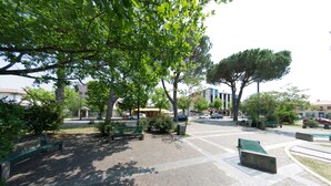A paved pedestrian area with benches and trees. - Hotel Tessarin (Taglio di Po)