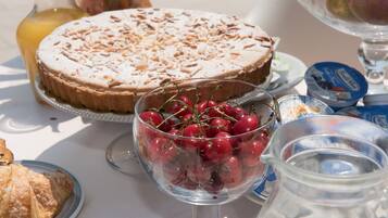 A table with a cake, a bowl of cherries, and a pitcher of milk.
