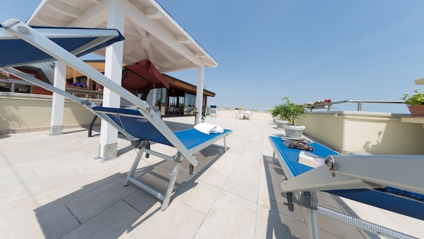 A rooftop terrace with two sun loungers, a table, and a potted plant. - Hotel Tessarin (Taglio di Po)